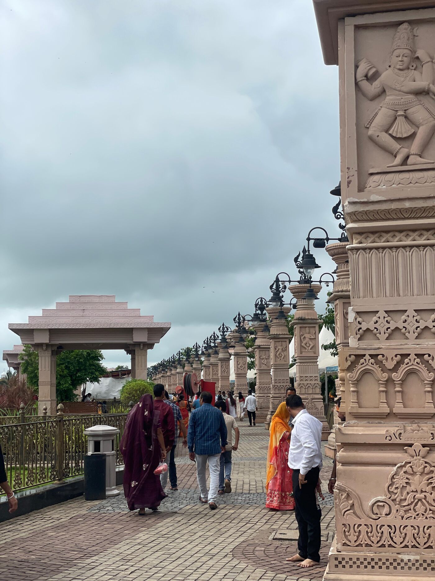 Visitors walking along a paved path lined with carved stone pillars and lamps