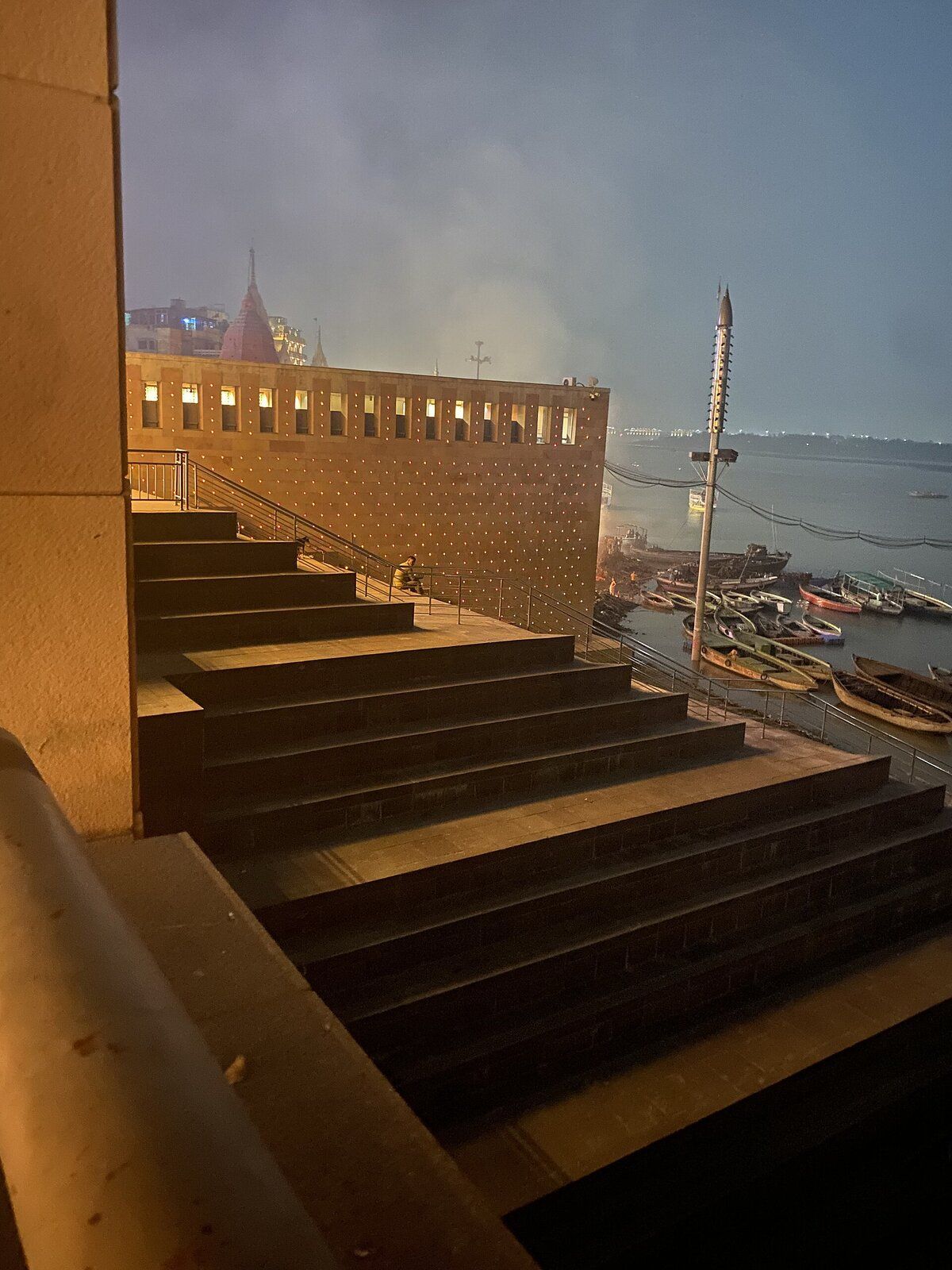 Wide stone steps going down from the corridor towards the river at dusk