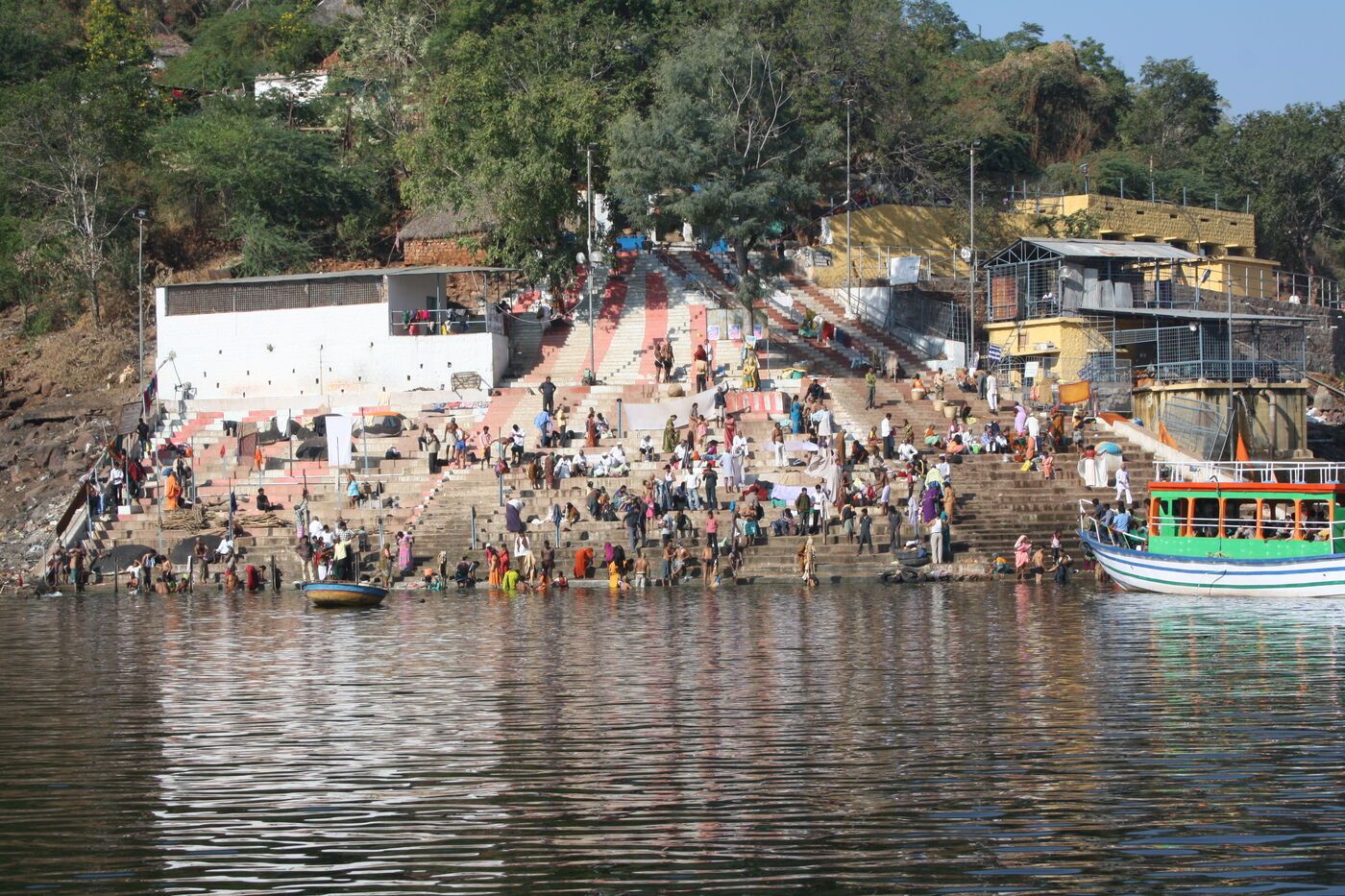 Pilgrims on stone steps going down to the river, with a boat at the water's edge
