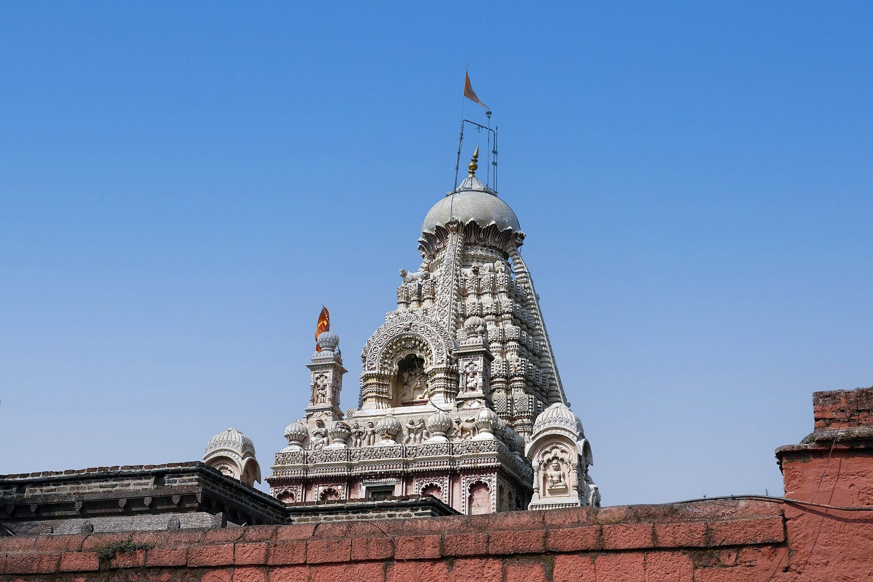 Close view of the temple's carved shikhara, with small carved turrets around it, against a deep blue sky