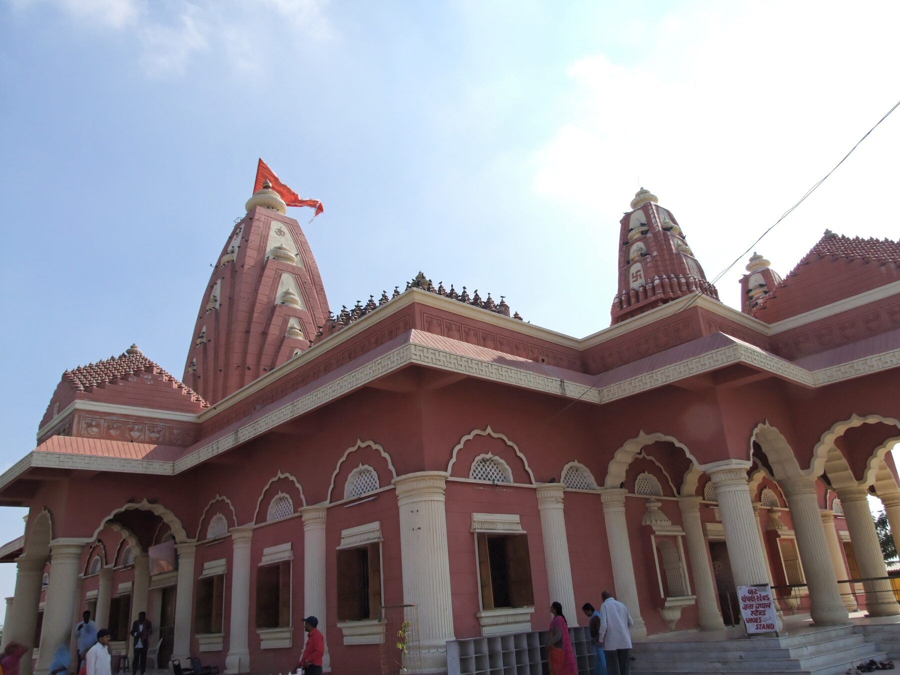 The pink and red Nageshwar temple building with carved spires, arched verandas and a saffron flag