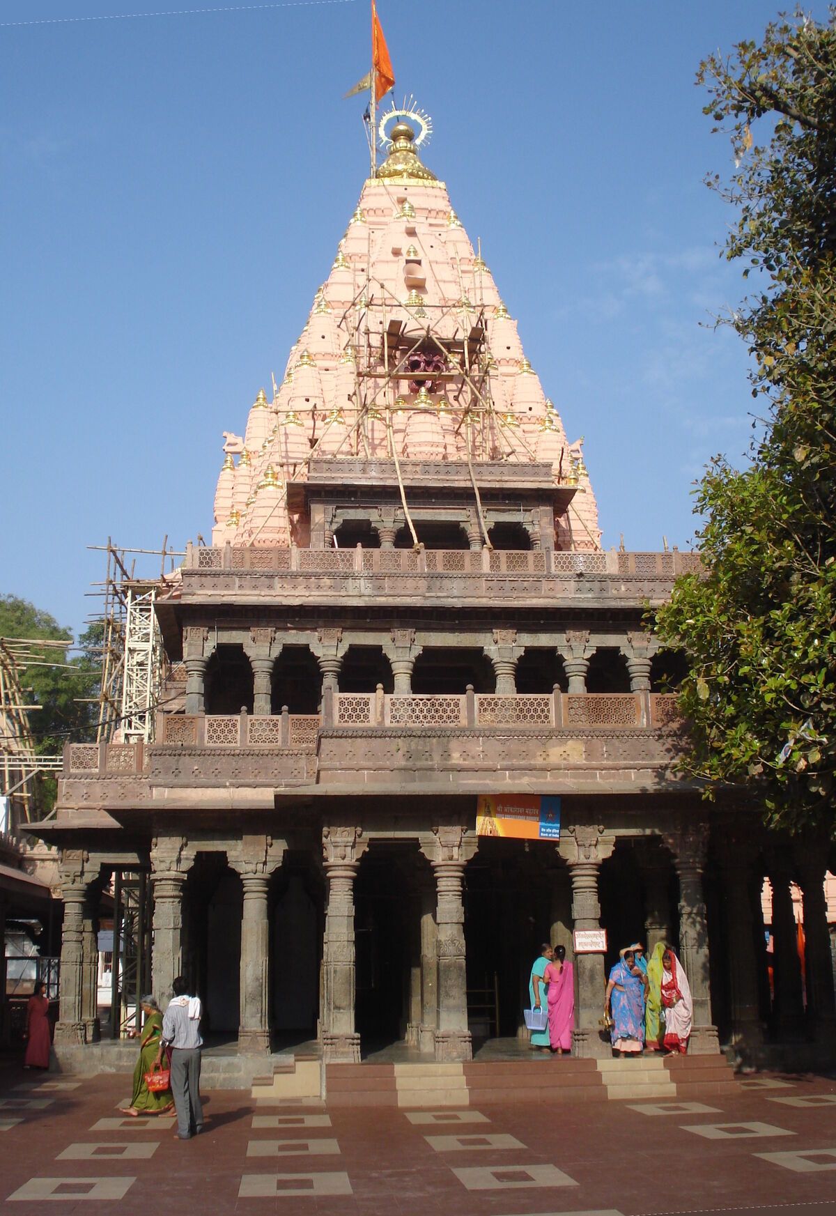 The pale stone spire of the temple above a pillared hall, under a blue sky