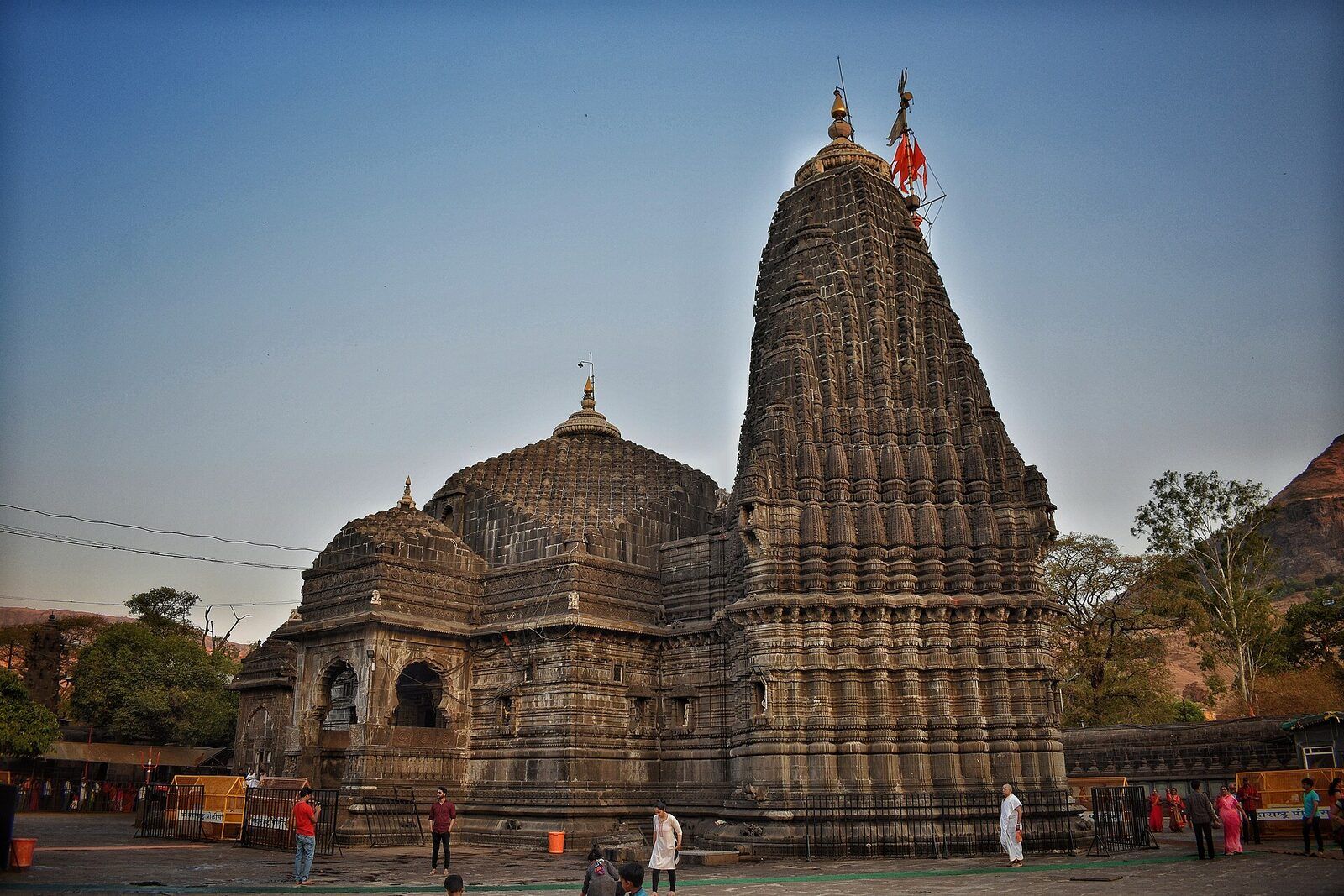 The dark stone temple in evening light, with a tall carved spire beside a lower domed roof